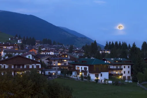 Mountain village lit at dusk under a moon