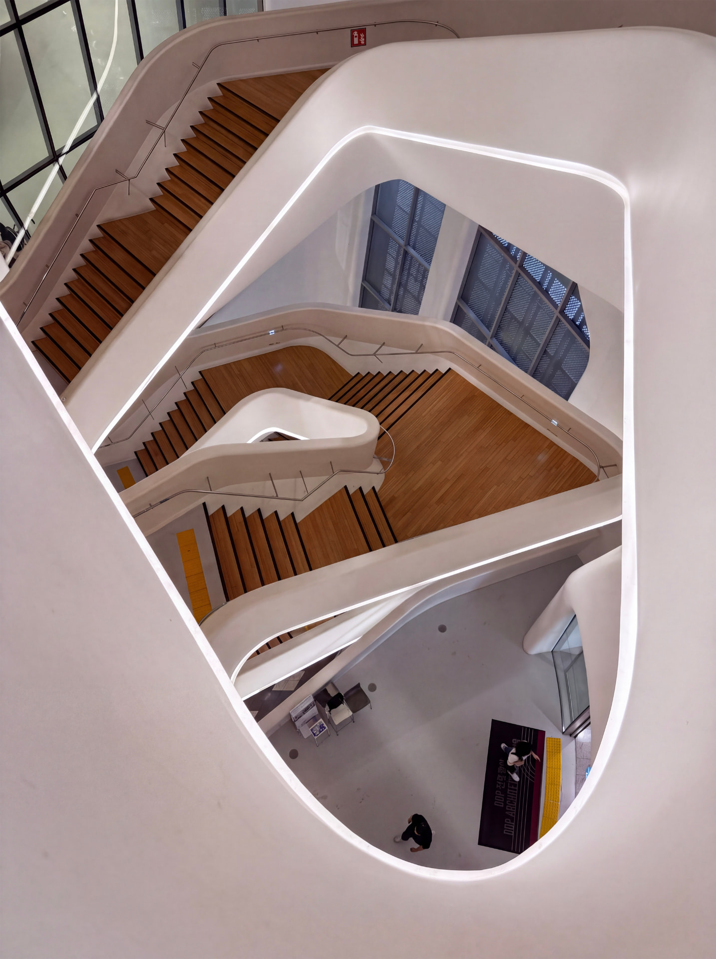 Curved white interior of Dongdaemun Design Plaza with a wooden staircase spiralling down