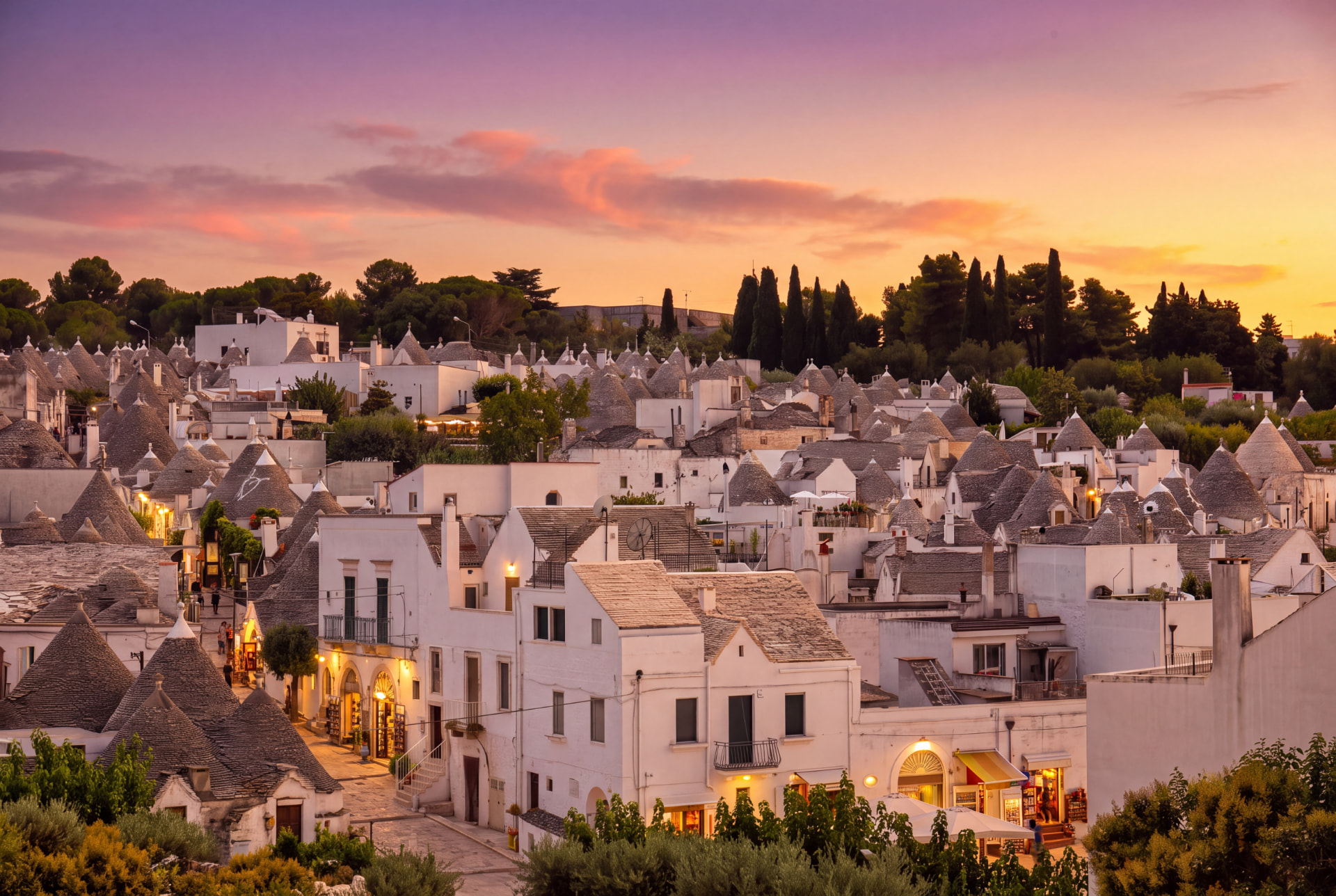View over the white conical roofs of Alberobello's trulli at sunset