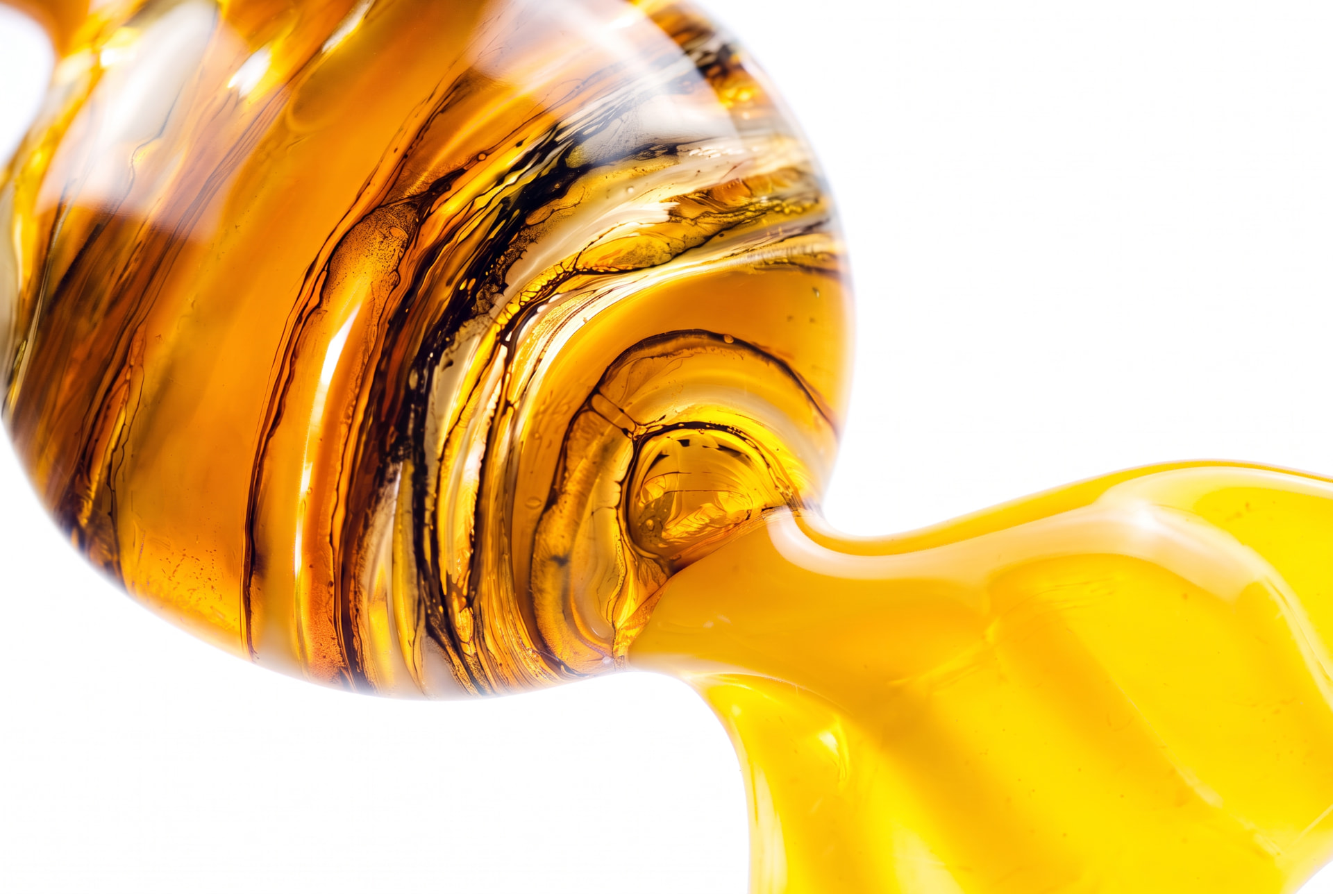 Close-up of golden amber liquid swirling with dark streaks against a white background