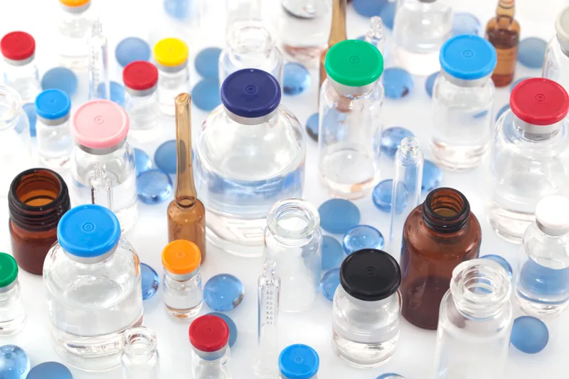 Glass vials and blue beads on a white surface